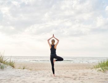 woman practicing yoga on the beach
