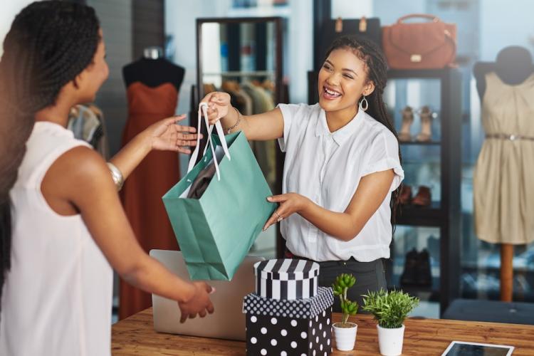 Cropped shot of a young store owner handing a parcel to a customer over the counter.
