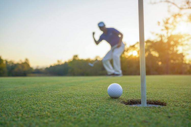Golfer action to win after long putting golf ball on the green