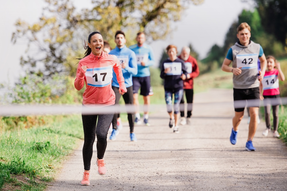 Large group of multi generation people running a race competition in nature.